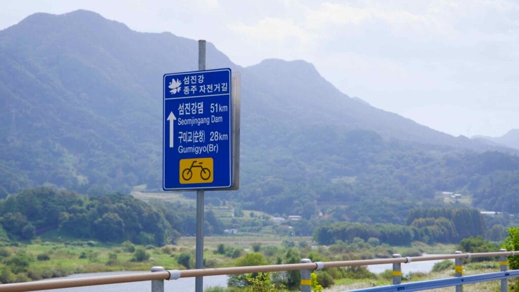 A directional sign along the Seomjingang Bike Path points toward Seomjingang Dam.