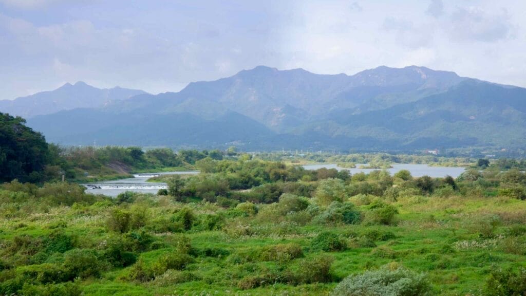 Scenic Seomjingang River surrounded by lush greenery and distant mountains.