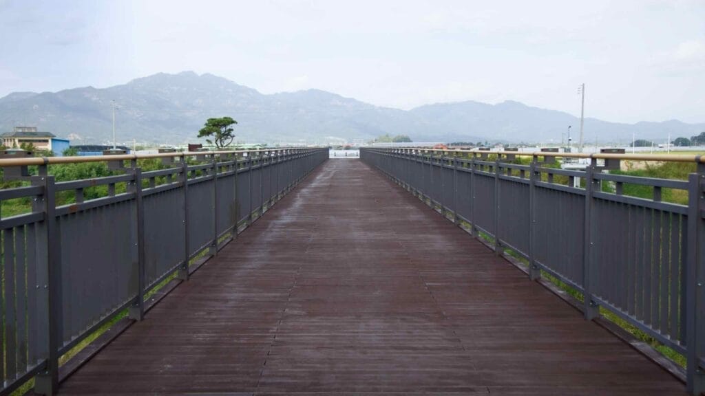 Scenic bicycle bridge on the Seomjingang Bike Path amidst green landscape and distant mountains.
