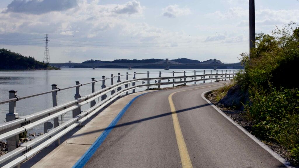 A winding section of the Yeongsangang Bike Path runs along the water’s edge, with a bridge spanning