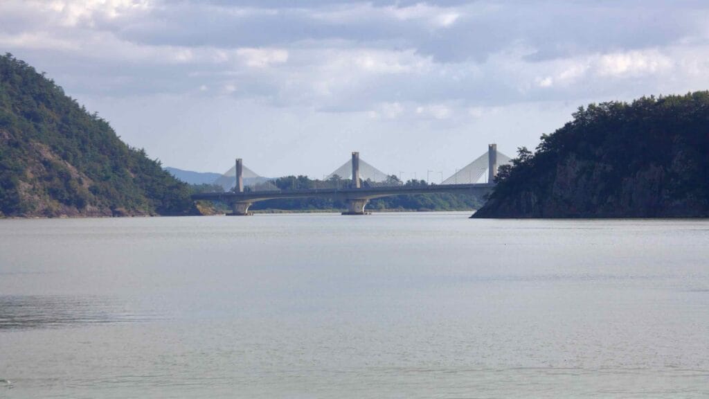 Muyeong Bridge spans the Yeongsangang River, framed by forested hills on either side.