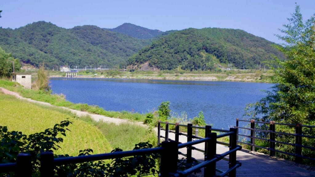 A footpath with railings overlooks the Yeongsan and distant hills.