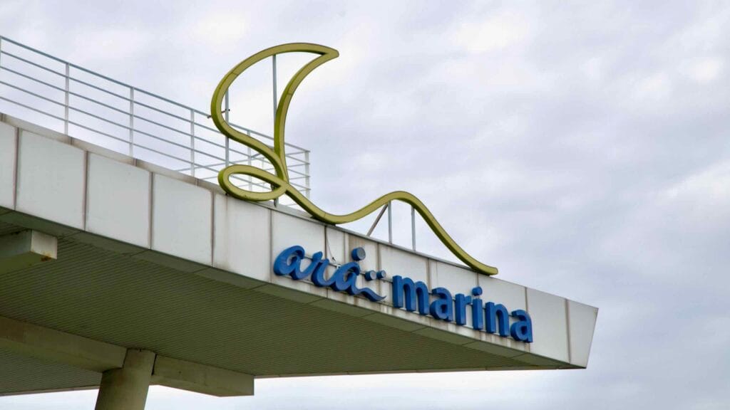 A close-up view of the Ara Marina rooftop signage shows its distinctive logo shaped like a sail, symbolizing the waterfront leisure hub along the Ara Waterway.
