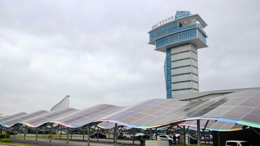 The Ara Waterway Observation Tower rises behind a wave-shaped parking canopy fitted with solar panels, showcasing sustainable design near the start of Korea’s bike trail.