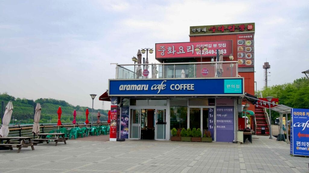 Aramaru Rest Area offers coffee, convenience, and canal-side dining for cyclists and visitors along the Ara Waterway, with a café and Chinese restaurant above.