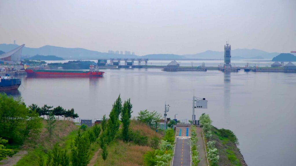 A close view of the Ara Waterway approaching the West Sea Lock, where cargo ships and lock gates connect the canal to the Yellow Sea, marking the start of Korea’s bike path.