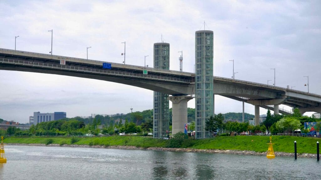 Gyeyang Bridge spans the Ara Waterway with twin glass elevator towers providing access between the riverside park and elevated roadway.