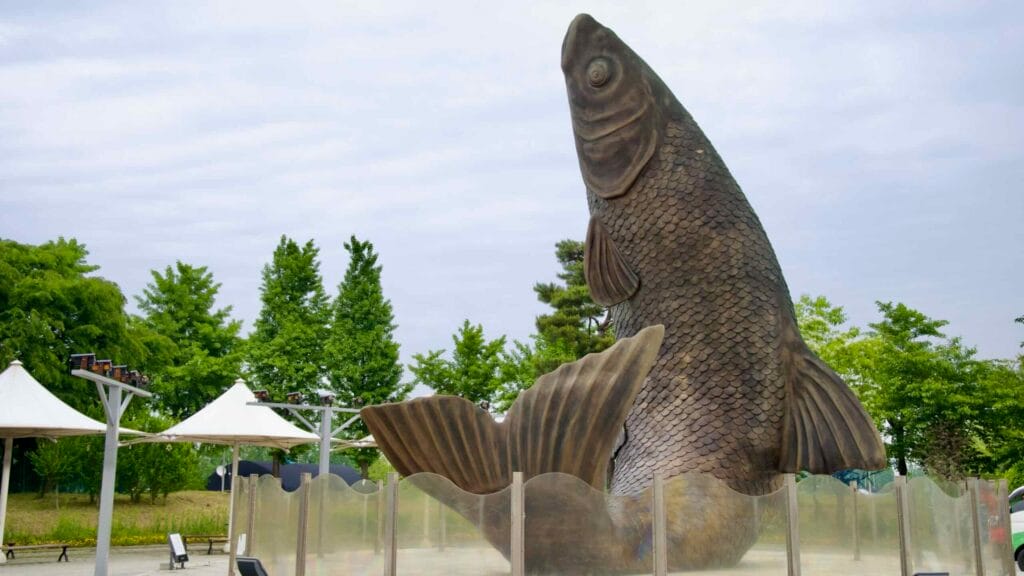 A towering fish sculpture rises from a mist-ringed fountain base in the Gyeyang Arabatgil Plaza, symbolizing the Ara Waterway’s aquatic heritage.