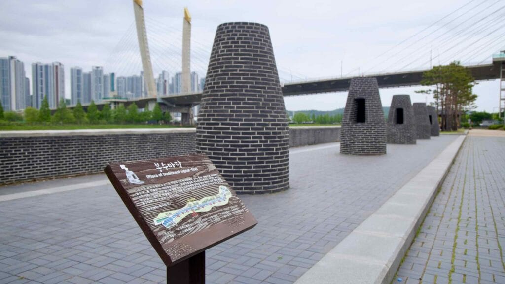 A modern plaza along the Ara Waterway features black brick structures modeled after traditional Korean signal-fires, once used to relay urgent messages across long distances.