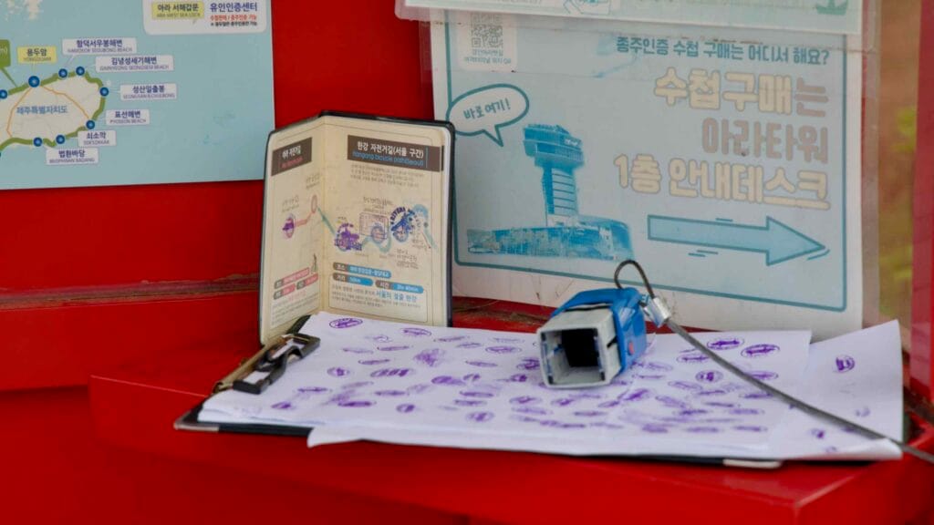 A close-up view of the stamp station inside the Ara West Sea Lock certification booth, where cyclists mark their Korea cross-country bike passports with official seals.