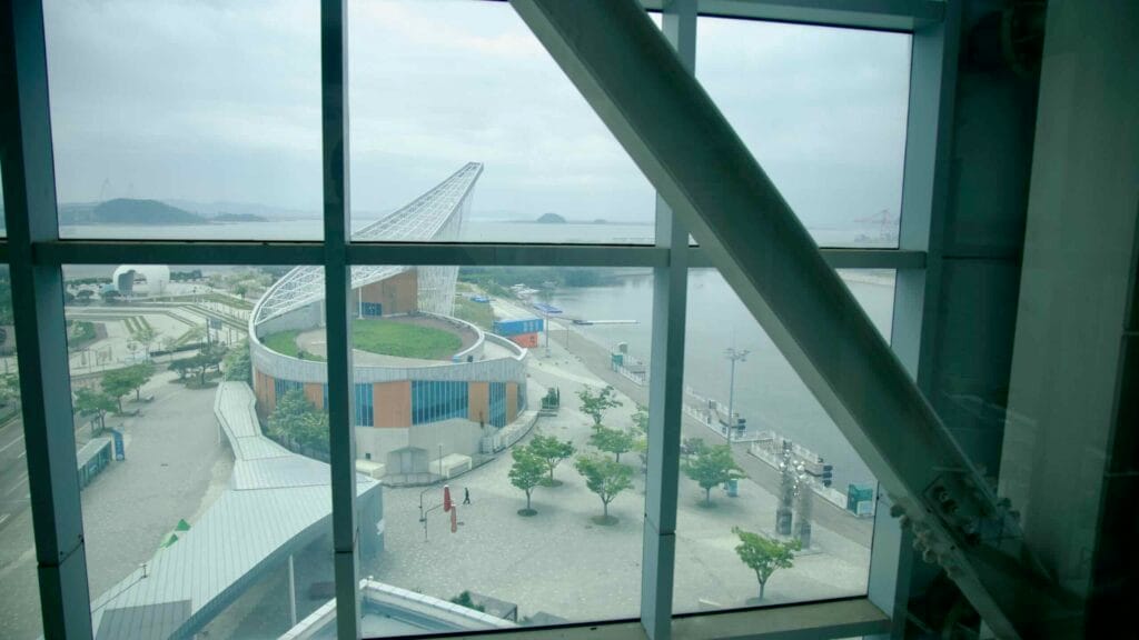 Looking out from the Ara Observatory, visitors can see the curved roof and waterfront of the Gyeongin Ara Passenger Terminal, set against the backdrop of the Yellow Sea and nearby islands.