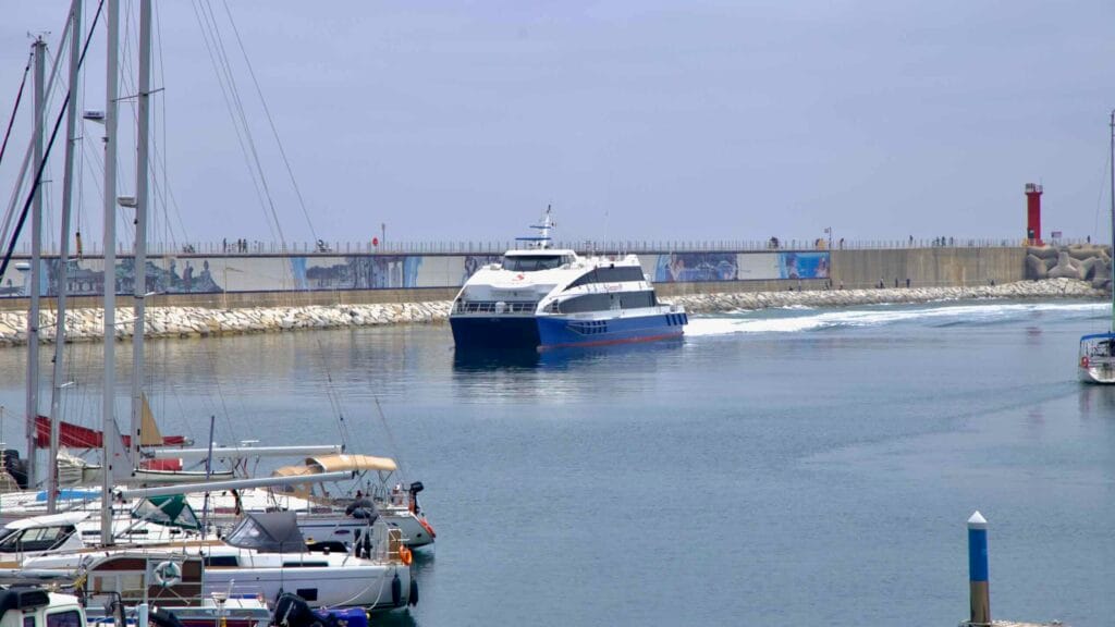Passenger ferry at Gangneung Port, passing docked boats under an overcast sky.