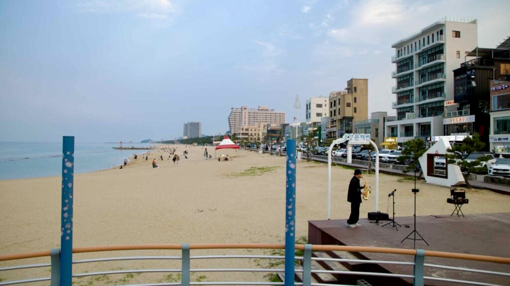 Street musician prepares to perform on a small stage by Gangmun Beach.