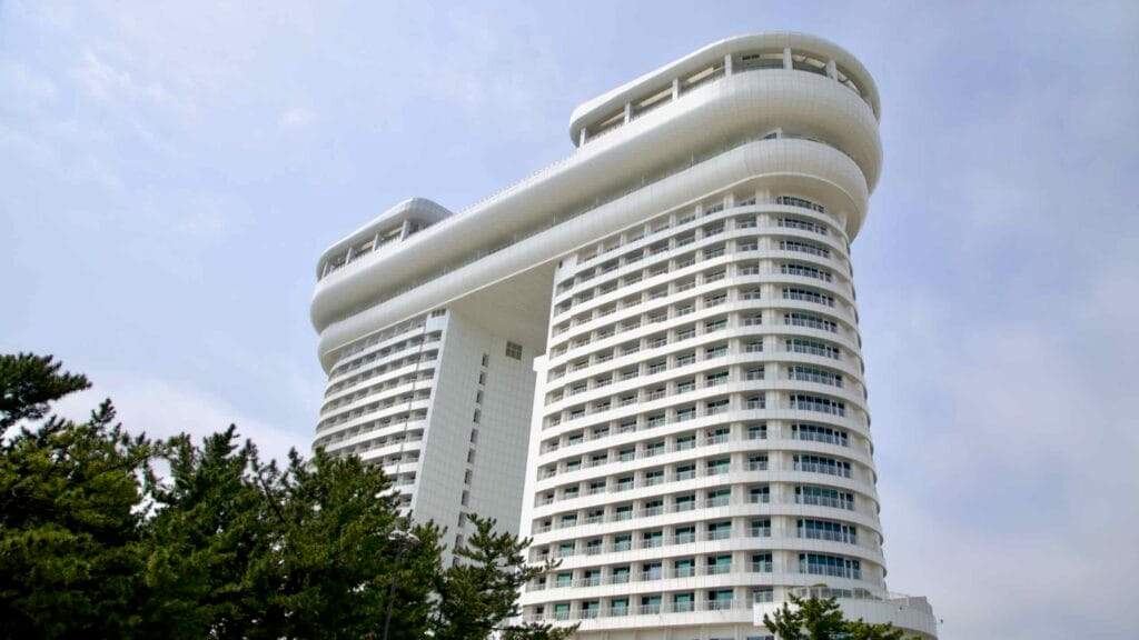 Skybay Hotel Gyeongpo's twin towers and curved skybridge, reflecting haze on the East Sea shore.