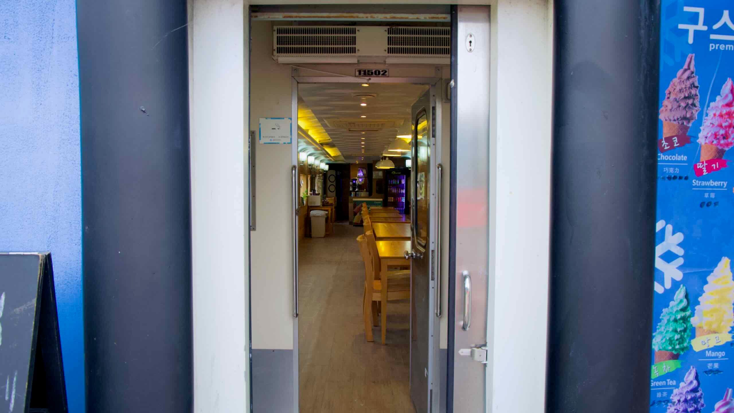 A look inside the train café near Neungnae Station reveals wooden tables, warm lighting, and refreshments for cyclists along the Bukhangang Bike Path.