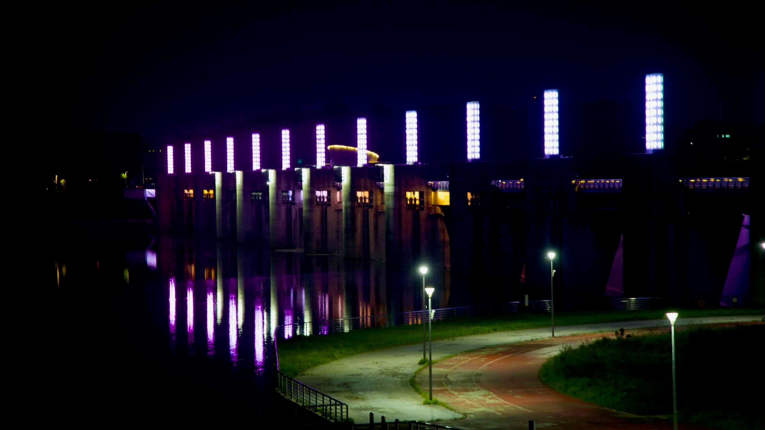 A bike path curves along the riverbank beneath glowing purple pillars of Yeoju Weir, part of Korea’s Four Rivers Project inspired by King Sejong's scientific legacy.