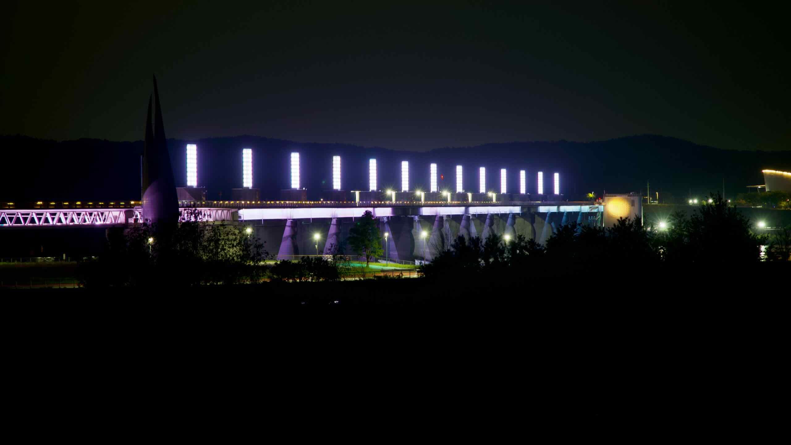 From across the river, the full span of Yeoju Weir glows beneath its twelve illuminated pillars, with the observatory tower visible at the structure’s western edge.