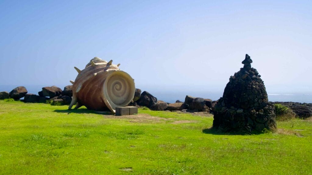Horn‑conch sculpture and lava‑stone cairn at Bbulsola Park.
