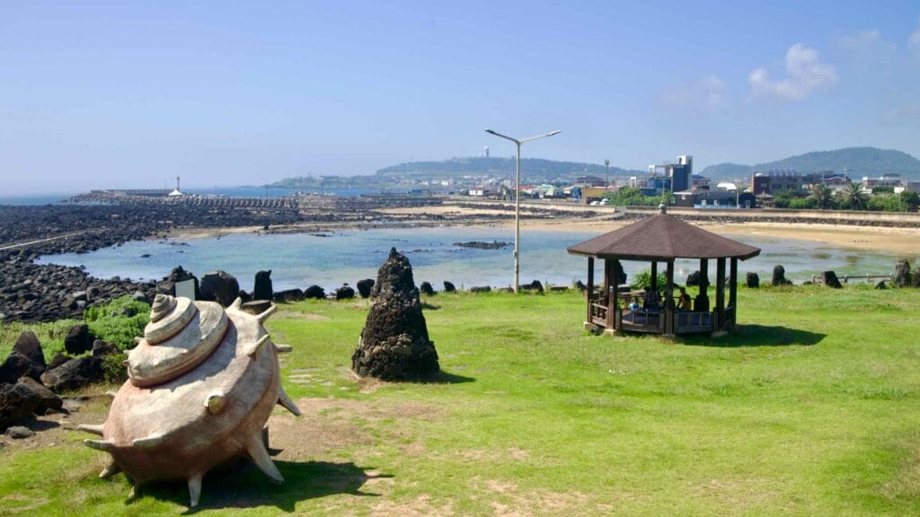 Horn‑conch sculpture and pavilion overlooking harbor and tidal pools.