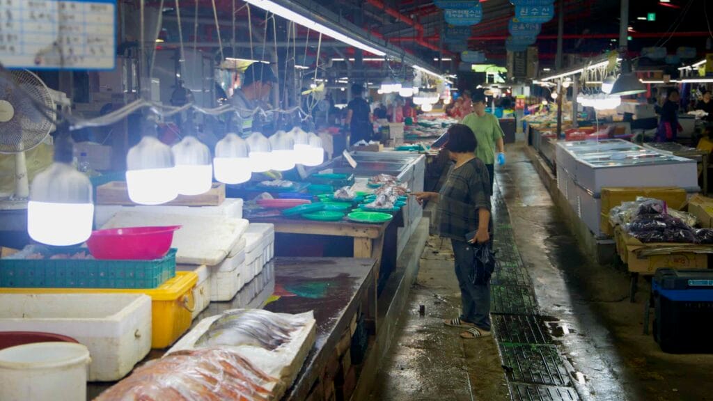 Bright lamps over a busy seafood aisle at Daejeong Five‑Day Market.