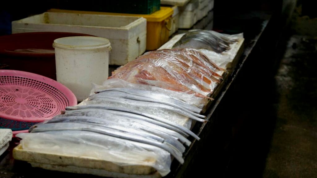 Hairtail and red fish laid out on ice at the market.