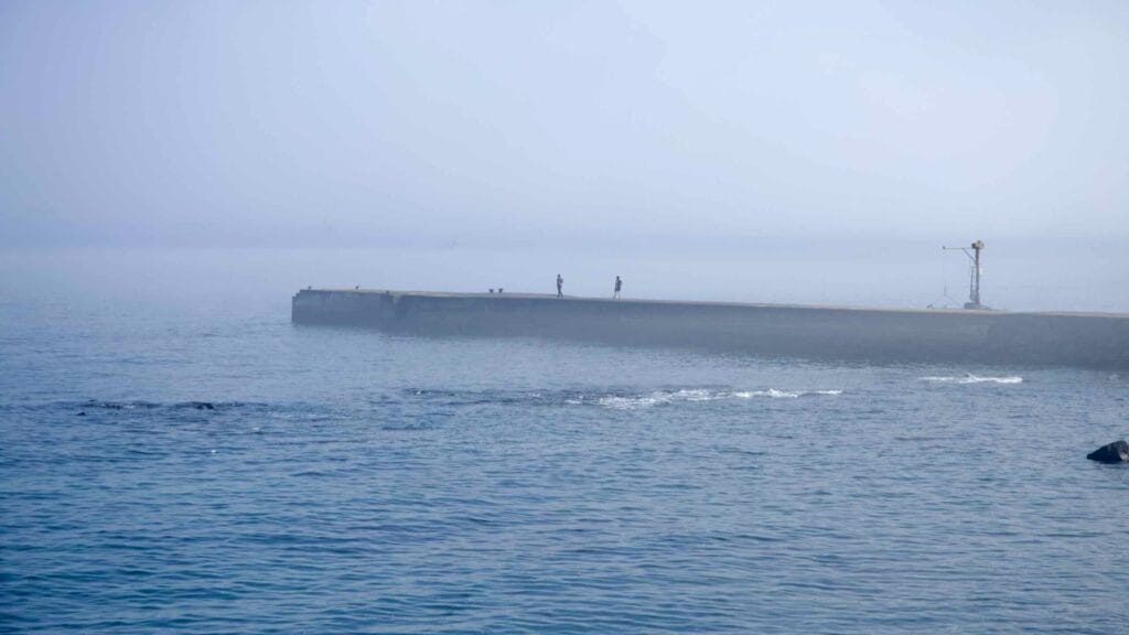 A foggy breakwater extends from the coast near Pan‑Pacific Peace Park by Songaksan.