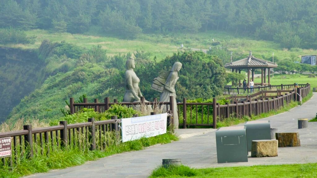 Stone figures and a wooden pavilion line the cliff‑top walkway at Songaksan.