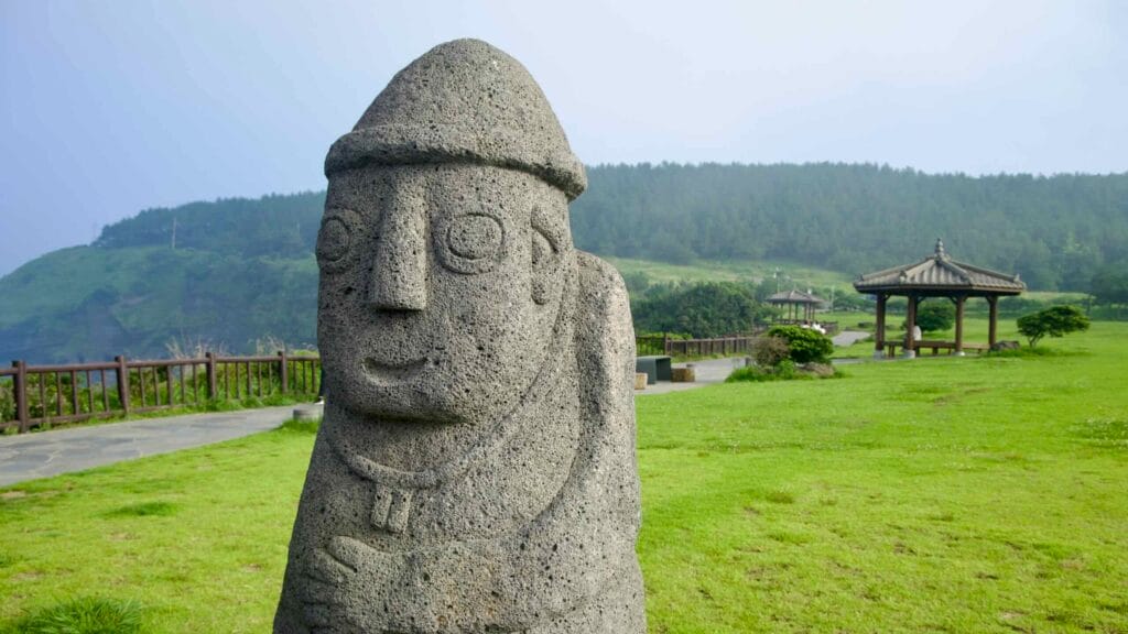 A close view of a dol hareubang statue on a grassy overlook at Songaksan.