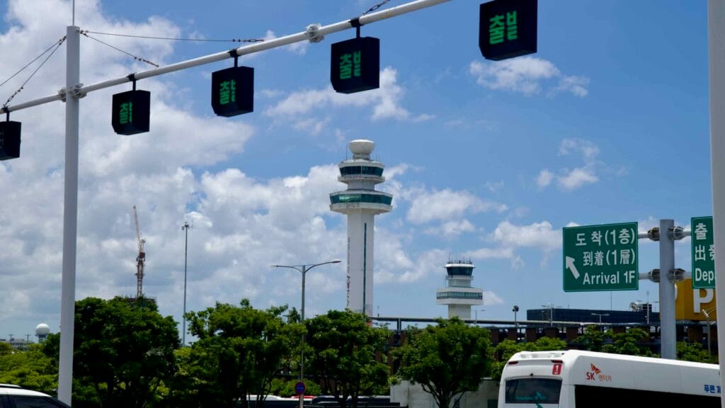 Air traffic control towers and road signs at Jeju International Airport.