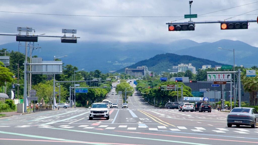 Jeju City boulevard leading toward Hallasan under summer clouds.
