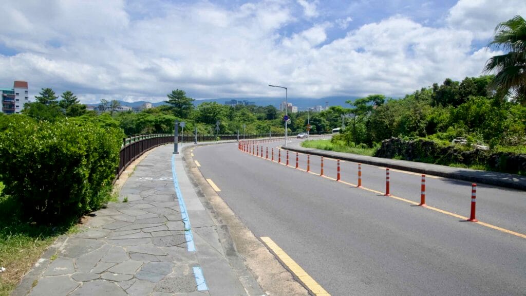 Curved approach road and stone sidewalk near Yongyeon Valley, Jeju City.