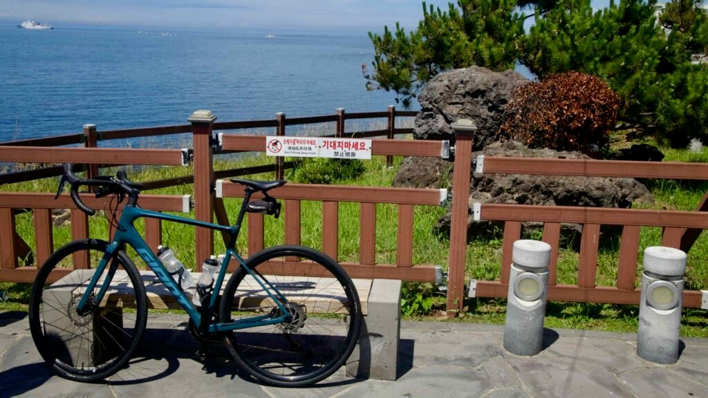 Road bike at a seaside rest point on Jeju’s coastal route.