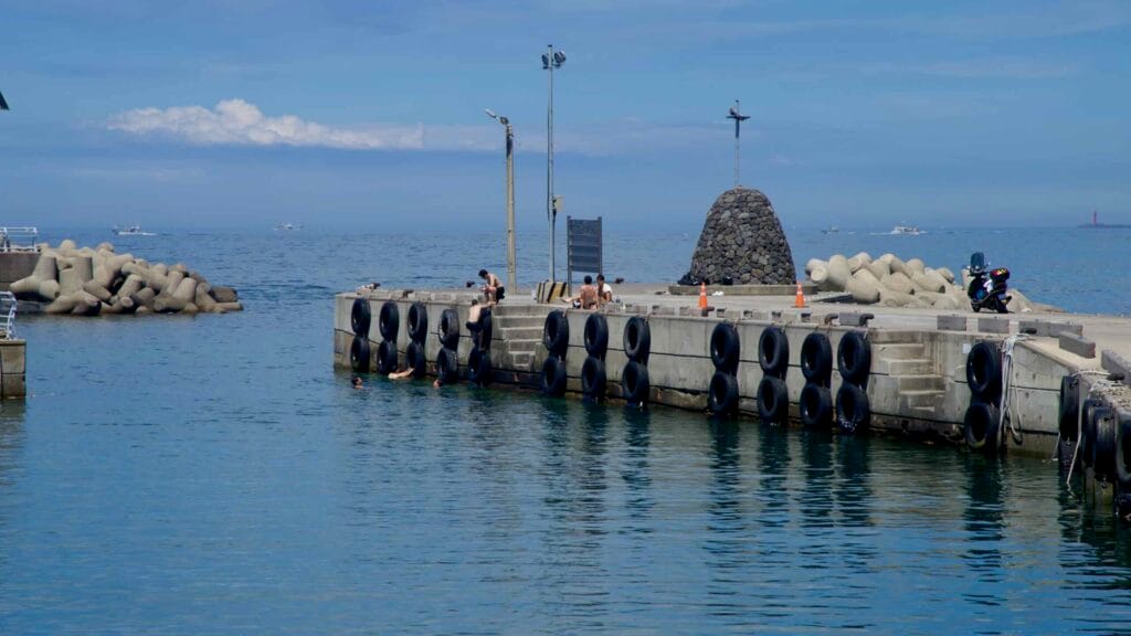 Swimmers gather along the tire‑lined breakwater at Yongdam Port.