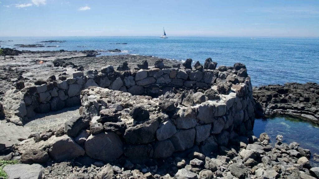 Stone enclosures and tidal pools on the basalt shelf at Eoyeong Park.
