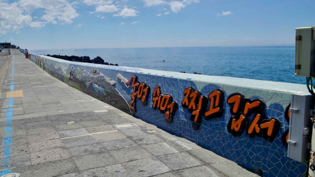 Tiled mosaic seawall with raised lettering at Eoyeong Park.
