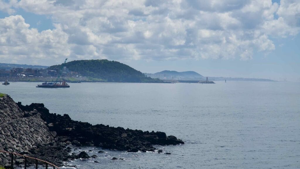 View from Eoyeong Park toward a green headland and red lighthouses.