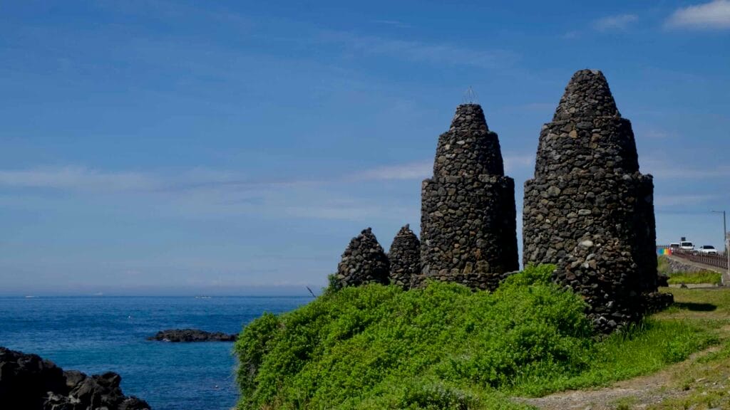 Cone-shaped Bangsatap towers overlook basalt rocks and sea.