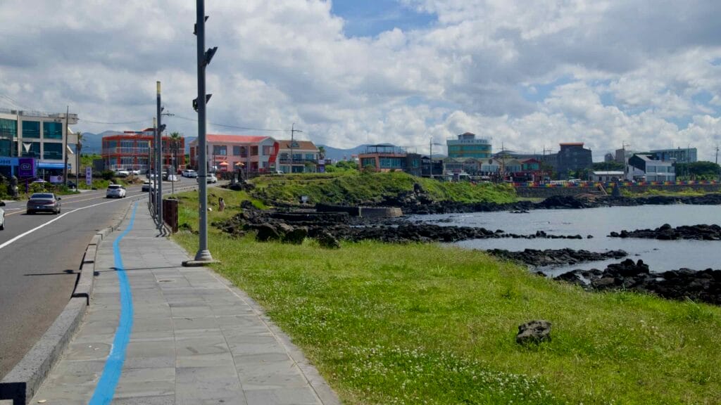 Blue-striped waterfront sidewalk leading toward Sasu Port shops.