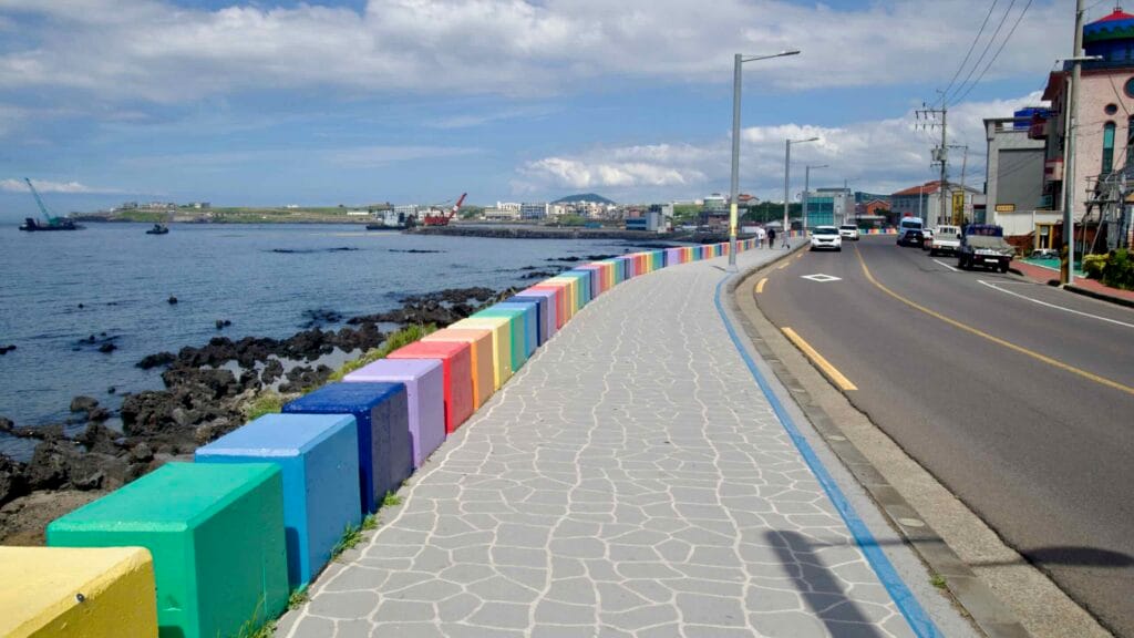 Color‑blocked rainbow seawall lining the Jeju Rainbow Coastal Road.