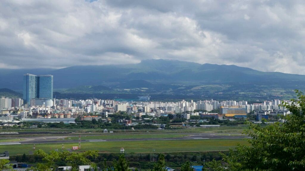 Jeju City skyline with Hallasan wearing a cap of clouds in the distance.