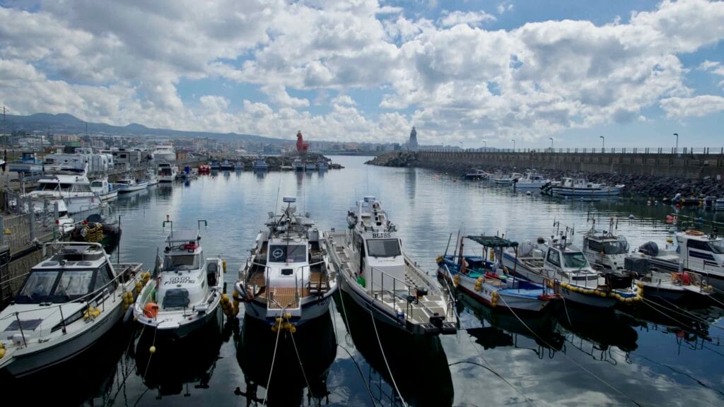 Boats rest in Iho Port near horse-shaped lighthouses.