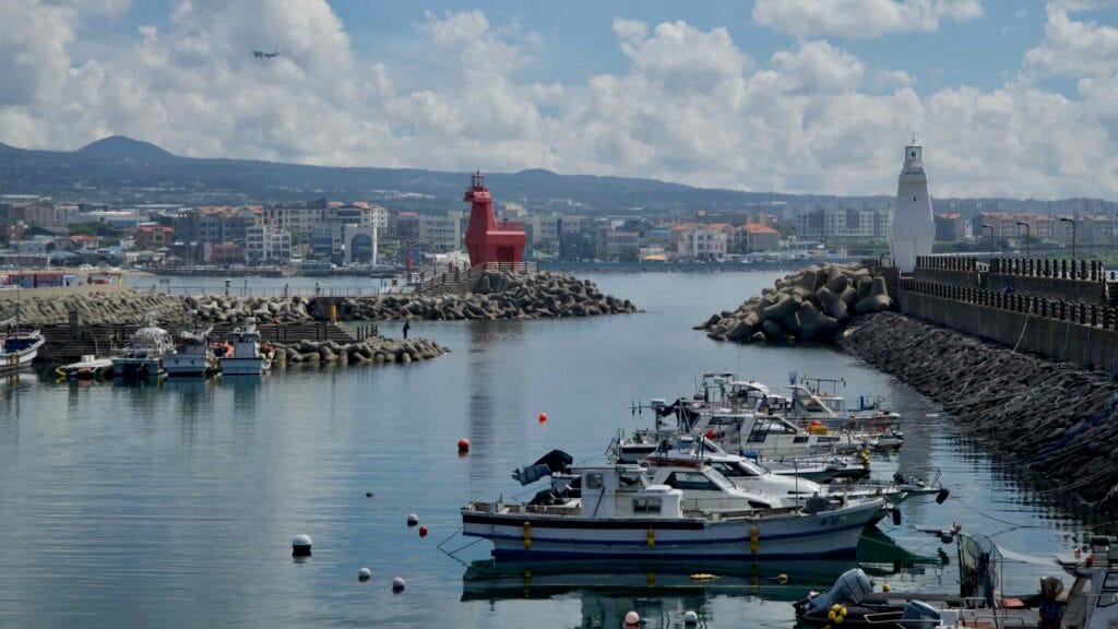 Small fishing boats moor between Iho Port’s playful horse‑shaped lighthouses.