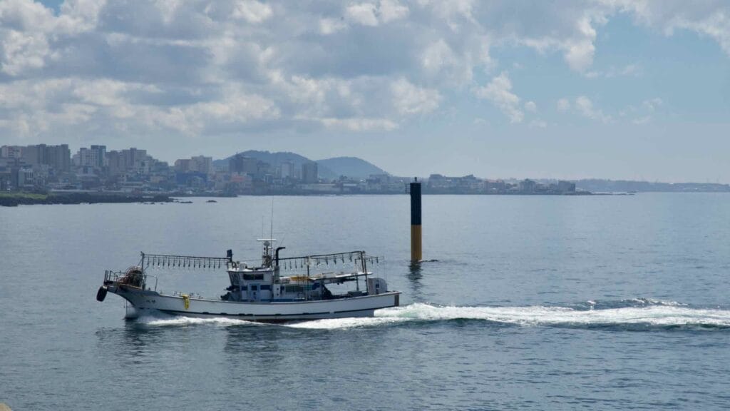A fishing trawler motors past channel markers off Jeju City’s north coast.