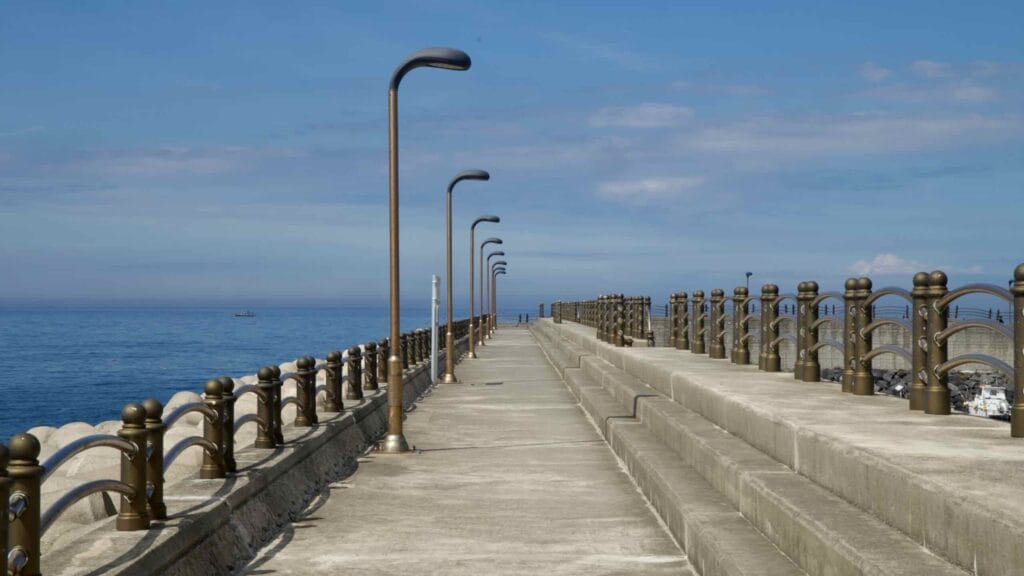 Symmetrical walkway along the Iho Port breakwater features bronze railings.