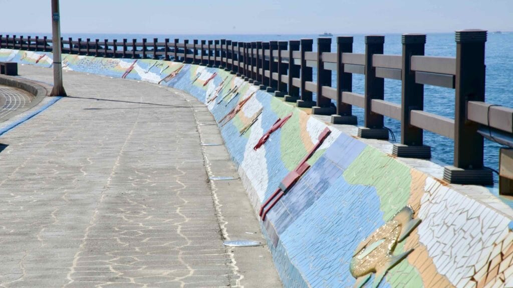 Close view of mosaic seawall reliefs by the sea.