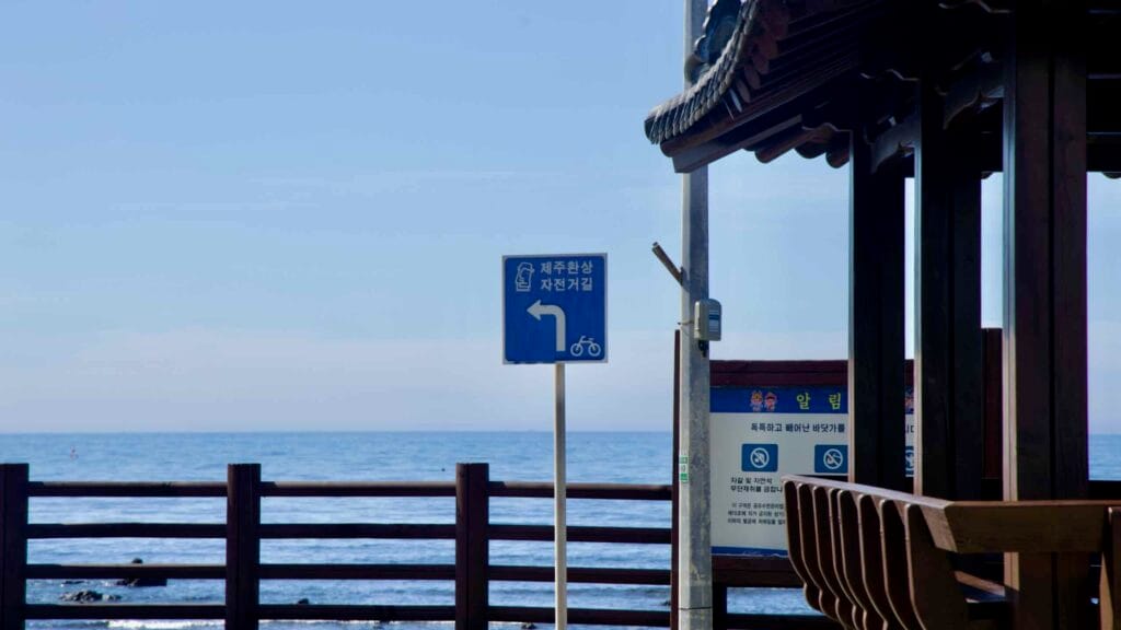 Round‑island bike path sign by a pavilion.