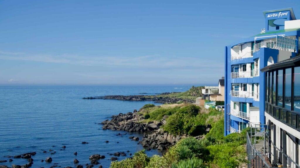 Blue hotel perched above a rocky inlet.