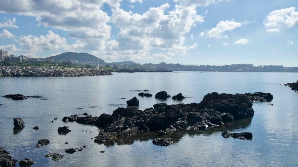 Basalt rocks with a white lighthouse across Iho Harbor.