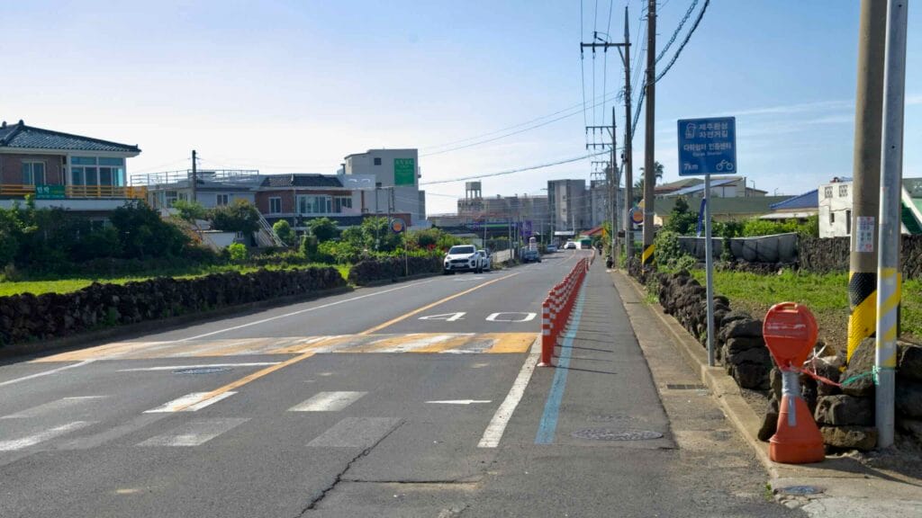 Aewol Town street on the Jeju Fantasy Bike Path with bike lane posts and stone walls.