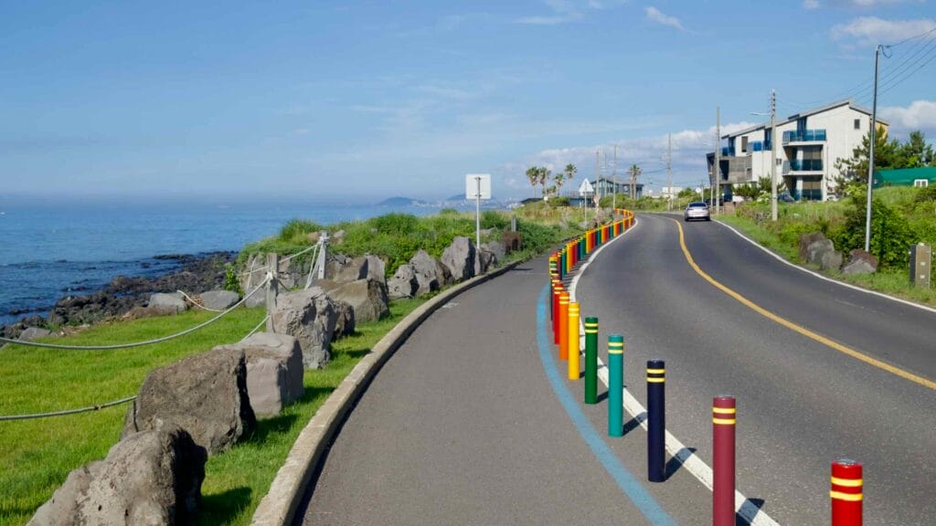 Hagu‑Aewol seaside bikeway with colorful posts by the rocky shore near Darak.